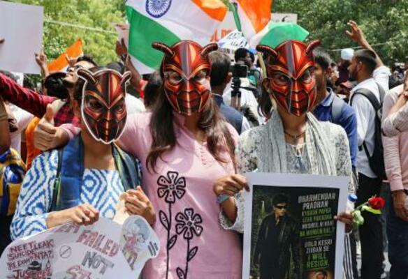 ゴキブリを模したお面をかぶった抗議集会の参加者=20日、インド・ニューデリー(共同)