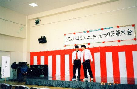 高校３年の時、地域のお祭りで相方の益子卓郎さん（右）と漫才をする（左）