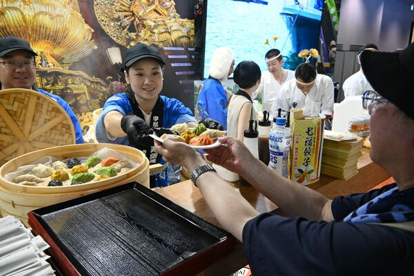 笑顔で料理を提供する本県ブースのスタッフたち＝29日午前10時15分、大阪市此花区の夢洲
