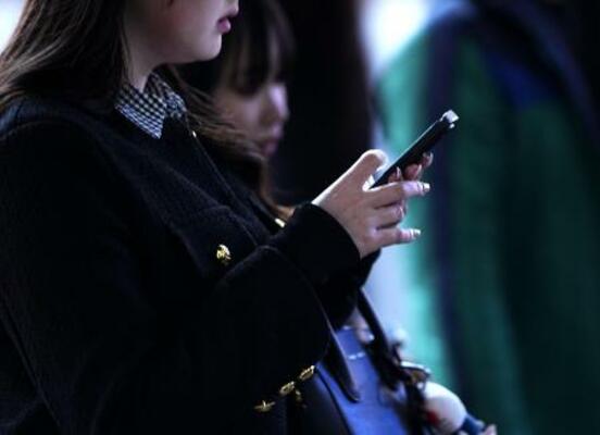 東京・渋谷のスクランブル交差点で、スマートフォンを手にする人=2025年2月