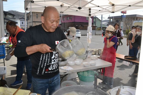 報告会で提供するラーメンを準備する和知さん（手前）
