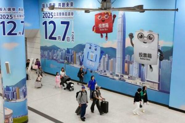 　駅構内の壁一面に張られた立法会選挙の投票を呼びかける広告＝６日、香港（共同）