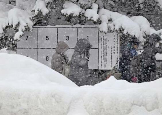 　雪でかすむ衆院選候補者のポスター掲示板＝２６日、札幌市