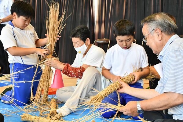 指導を受けながら豊年棒を作る児童