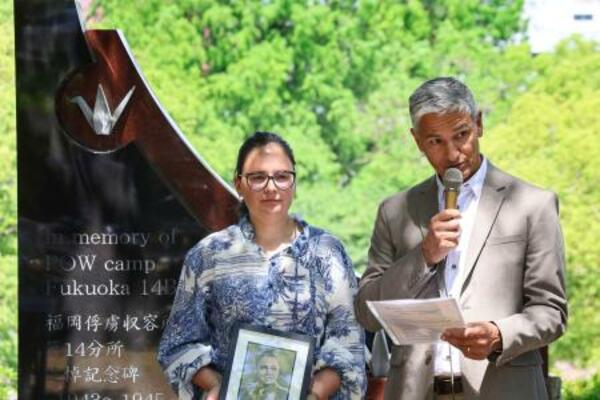 　外国人捕虜の追悼式でスピーチする遺族のクイントゥス・ファンデルベイルさん。左は娘のリサさん＝１０日午前、長崎市