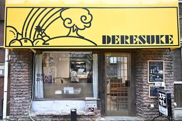 黄色地に描かれた店名やイラストが目を引くＰｕｂデレスケの外観