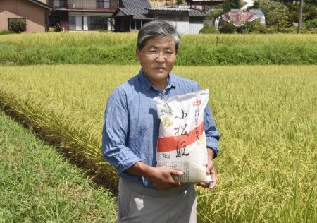 　ブランド米「真田のコシヒカリ　小松姫」を持つ金井繁行さん＝２０２５年８月、群馬県沼田市