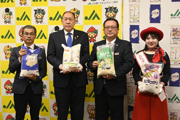 船田理事長（左から２人目）に新米を手渡した佐藤副本部長（同３人目）＝６日午前、宇都宮市