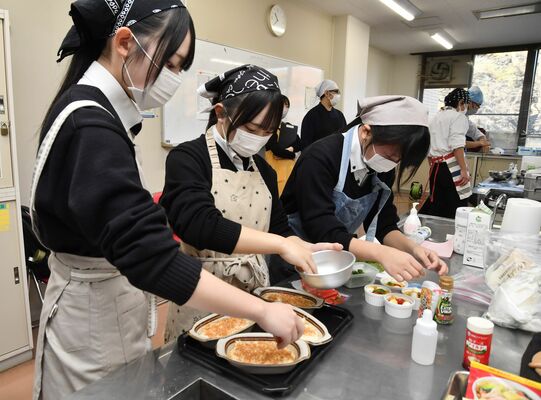 協力しながら調理する高校生