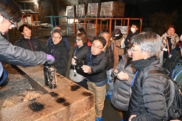 エチケットが腐食した熟成ワインを写真撮影する参加者＝１３日午前、宇都宮市