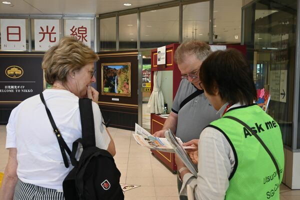 外国人観光客を案内する宇都宮ＳＧＧクラブのガイド（右）＝８日午前、ＪＲ宇都宮駅