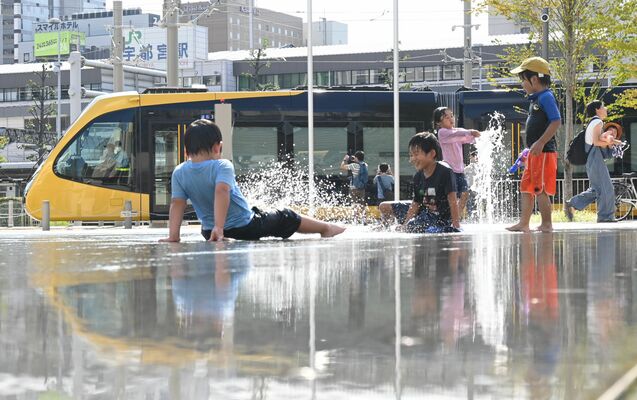 試運転するライトラインと水遊びを楽しむ子どもたち