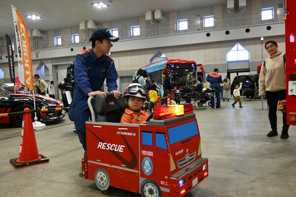 消防署員の服を着て、小さな消防車に乗る来場者=24日午後、宇都宮市元今泉6丁目