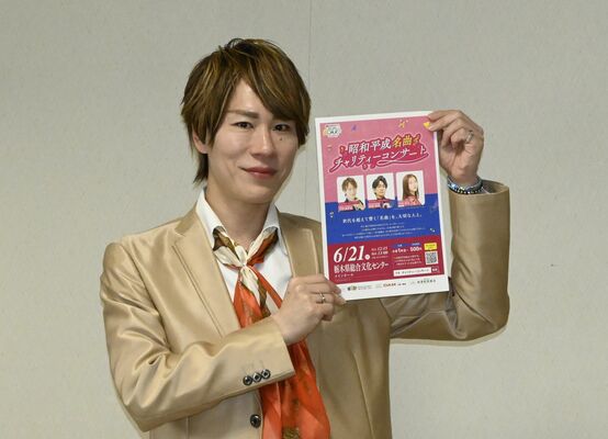 「昭和平成名曲チャリティーコンサート」のチラシを手に来場を呼びかける下司さん