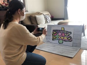 壁紙をボードに貼った背景を使って撮影する菊池さん