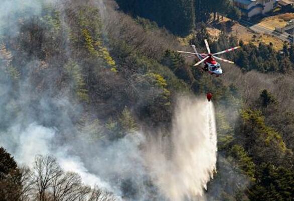山梨県上野原市の扇山で続く消火活動=10日午前9時25分(共同通信社ヘリから)