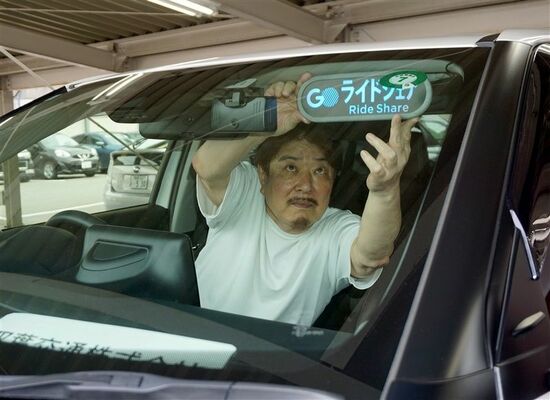 自家用車にライドシェアの表示を取り付ける一般ドライバーの井野和弘さん＝６月12日午後、福岡市