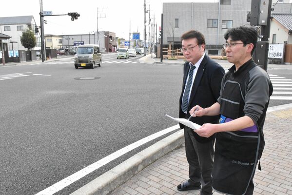 金燈籠交差点に立ち、資料を見ながら、ぶっつけ時の屋台の位置を確認する鈴木さん（手前）
