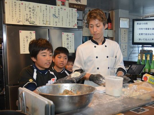 相原さん（右）の手ほどきを受けギョーザ作りを体験する子どもたち