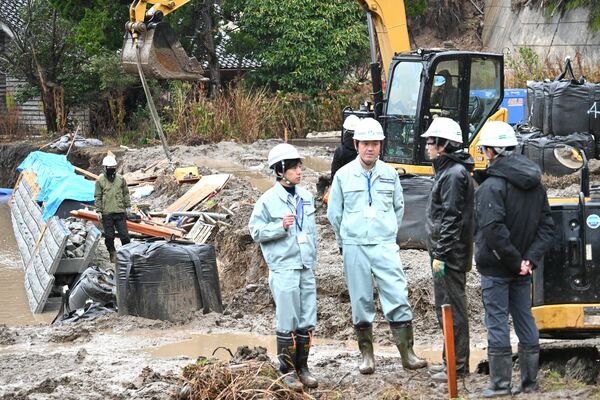 河川工事現場で工事責任者と作業状況を確認する金本さん(中央左)と小野さん(中央左から2番目)
