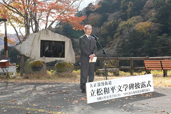 披露された文学碑の前であいさつする塩原文学研究会の千葉会長