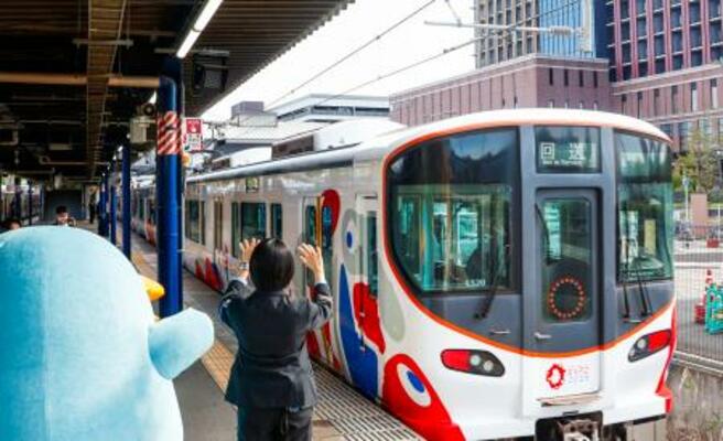 JR桜島駅でミャクミャク電車を見送る駅員ら=29日午前、大阪市此花区