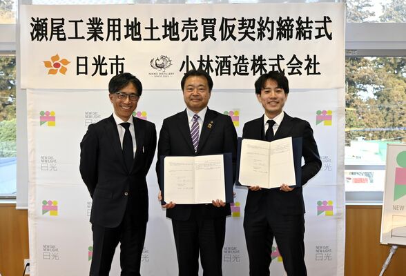 仮契約書を手にする（右から）小林勇輝氏、粉川市長、小林正樹社長＝23日午後、日光市役所