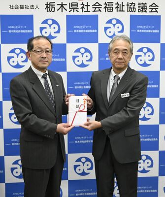 篠崎常務理事（右）に寄付の目録を手渡す岡村支部長＝26日午後、宇都宮市
