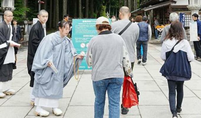 　高野山の金剛峯寺の奥之院入り口で、肩や足の露出が多い服装を控えるよう啓発する僧侶ら＝６日午前、和歌山県高野町