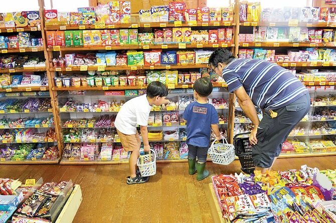 買い物かごを提げ、楽しげにお菓子を選ぶ子どもたち