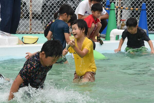 ずぶぬれになりながらマスを捕まえる子どもたち