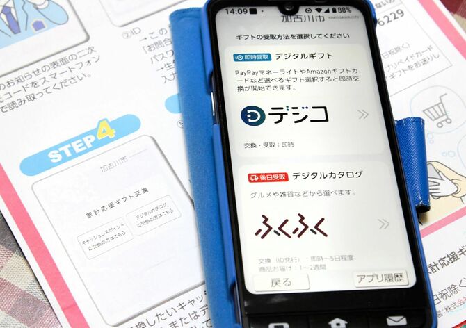 加古川の「家計応援ギフト」の案内文のイラスト（左下）と、スマホで申し込む際の実画面（右）。表示が異なっている
