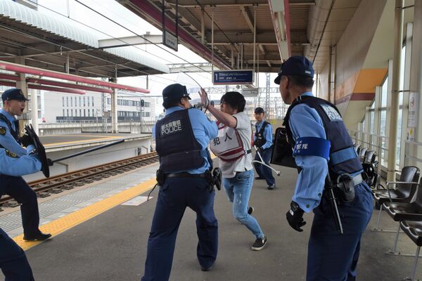 訓練で犯人役（右から３番目）を制圧する警察官