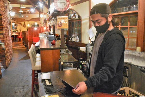 予約状況をタブレット端末で確認する倉西店主＝18日午後、宇都宮市宿郷５丁目