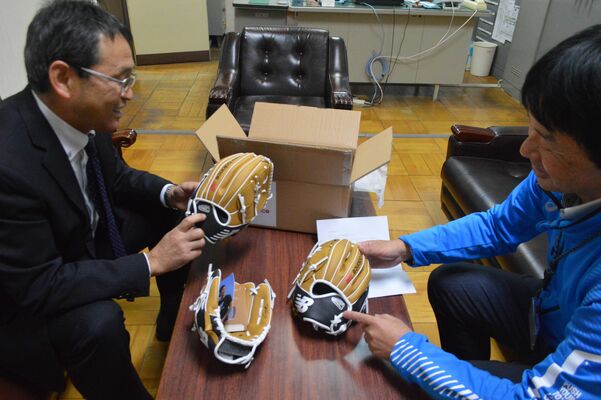 大谷選手から届いたグラブや手紙を確認する堀場校長（左）と宇都宮市教委の担当者＝25日午後、宇都宮市中央小
