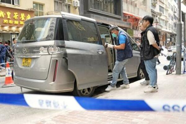 　香港の強盗事件で、近くの路上に残された容疑者が使ったとみられる車を調べる警察官ら＝１８日（共同）