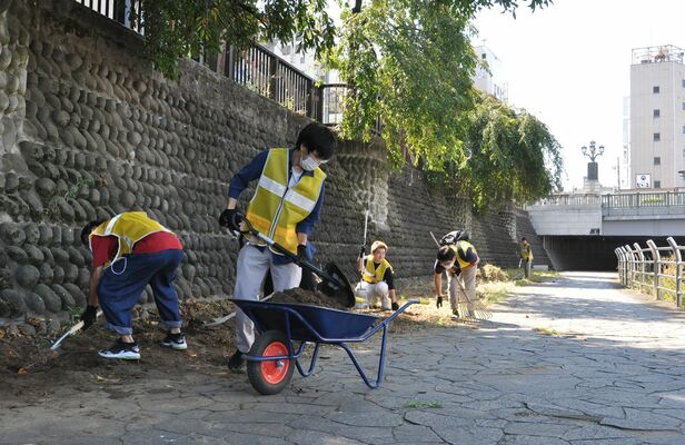 宮秋祭の会場となる田川遊歩道で清掃などを行う宇都宮共和大の学生たち
