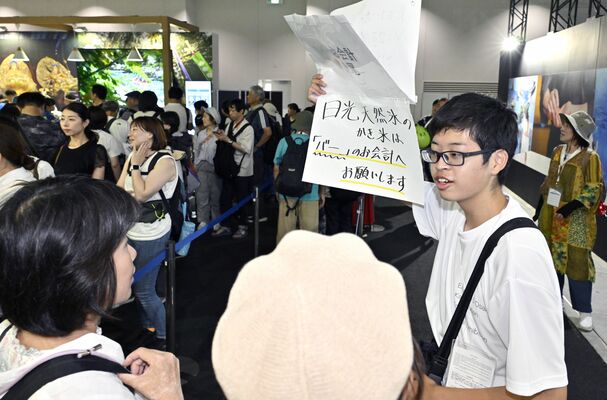 来場者に本県ブースを案内する小堀絢心さん（右）＝28日午後３時50分、大阪市此花区の夢洲