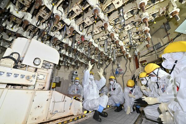 ５号機の原子炉圧力容器の真下を視察する取材班。頭上にあるのは制御棒の出力調整装置＝10日午後１時50分、福島県双葉町（超広角レンズ使用）