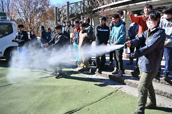 練習用のクマ撃退スプレーを試す生徒ら=6日午前、宇都宮市篠井町