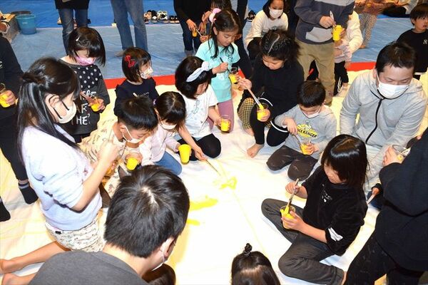 巨大キャンバスに絵の具を塗る子どもたち
