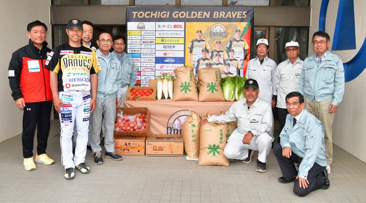 農産物を贈る小山市農業委員会の大塚会長（左から５人目）らと、栃木GBの寺内監督（左から２人目）ら＝小山運動公園野球場