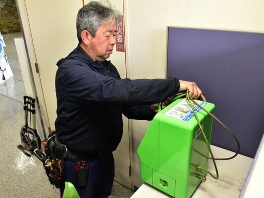 利用実績が少ない公衆電話の撤去作業＝４月、下野新聞社本社