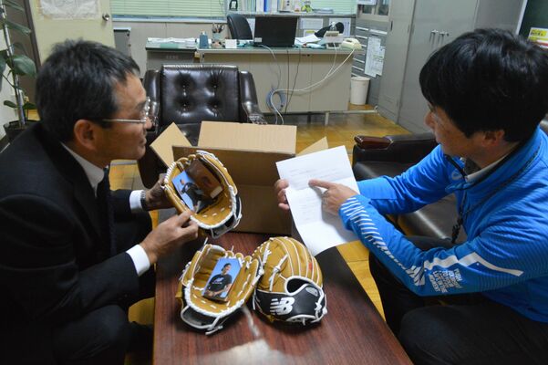 大谷選手から届いたグラブや手紙を確認する堀場校長（左）と宇都宮市教委の担当者＝25日午後、宇都宮市中央小
