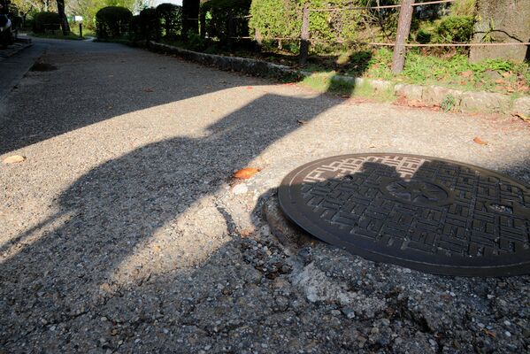 過去に哲学の道の一部区間で舗装工事が行われ、アスファルトに覆われた路面。ひび割れやくぼみが生じている