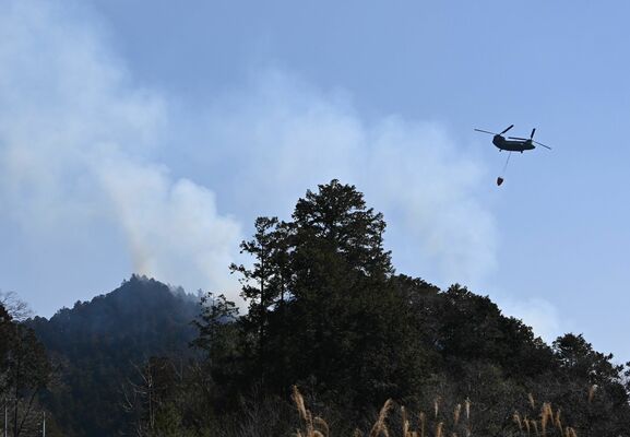 山林火災の消火活動に当たる自衛隊ヘリ=22日午前11時40分、鹿沼市上南摩町
