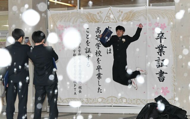 巨大な卒業証書の前で記念撮影する生徒たち