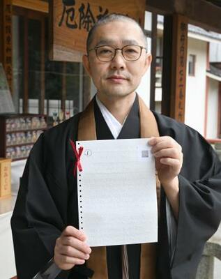 点字おみくじを持つ根本聖道さん=東京都中野区