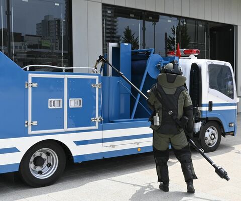 爆発物に見立てた紙袋を専用車両に収納する県警機動隊員＝５日午前、宇都宮市宮みらい