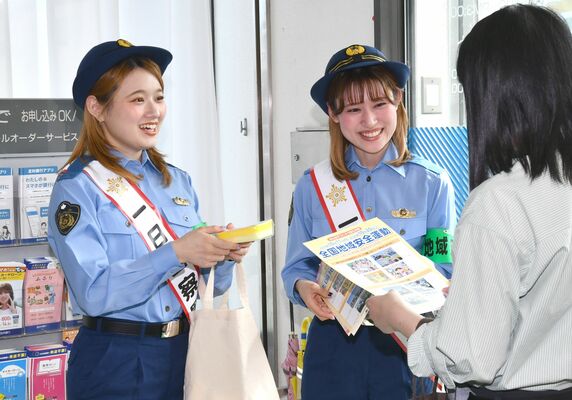 銀行内で全国地域安全運動のチラシを配るラヴィンズ